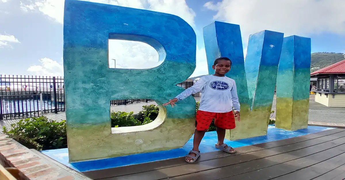 Young boy posing by a colorful BVI sign.