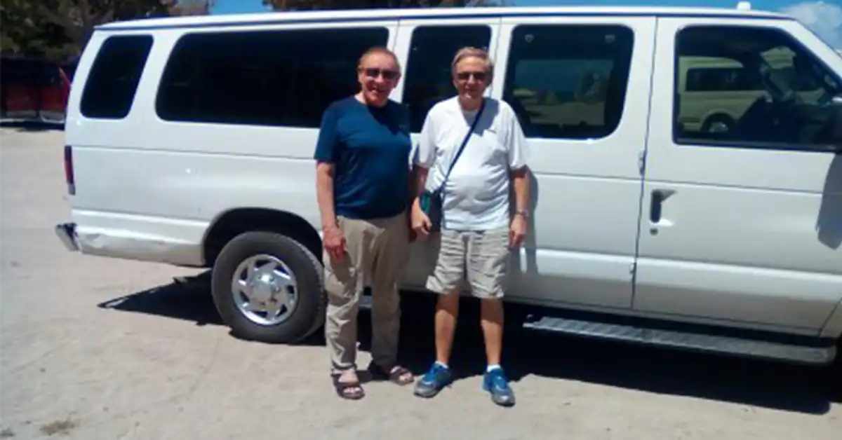 Friends standing beside a taxi van during their island visit.